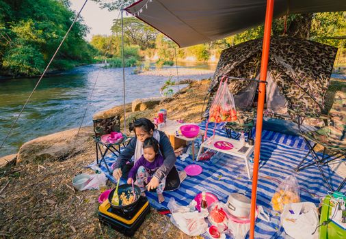 mother and child daughter cook omelet for breakfast between camping