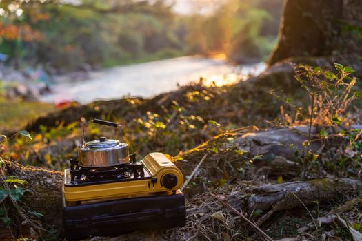 Picnic gas stove and aluminum teapot for boiling water during camping