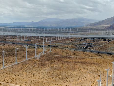 Aerial view of huge array of gigantic wind turbines spreading over the desert in Palm Springs wind farm. California. USA. Aerial view of wind turbines generating electricity. 