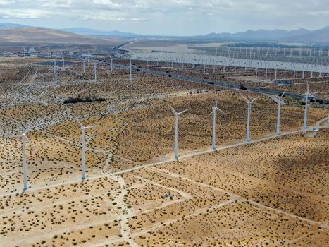 Aerial view of huge array of gigantic wind turbines spreading over the desert in Palm Springs wind farm. California. USA. Aerial view of wind turbines generating electricity. 