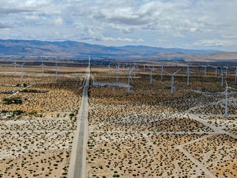 Aerial view of huge array of gigantic wind turbines spreading over the desert in Palm Springs wind farm. California. USA. Aerial view of wind turbines generating electricity. 