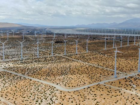 Aerial view of huge array of gigantic wind turbines spreading over the desert in Palm Springs wind farm. California. USA. Aerial view of wind turbines generating electricity. 