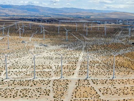 Aerial view of huge array of gigantic wind turbines spreading over the desert in Palm Springs wind farm. California. USA. Aerial view of wind turbines generating electricity. 