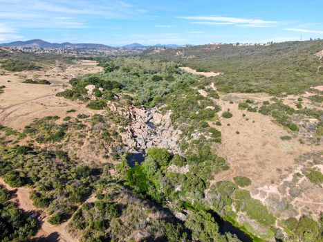 Aerial view of Los Penasquitos Canyon Preserve with the creek waterfall and people enjoying the water. Urban park with trails and river in San Diego, California. USA