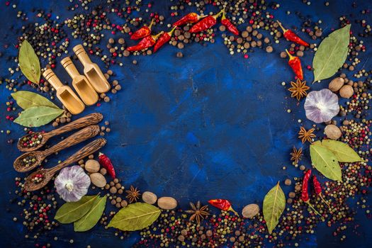 Various spices and wooden spoons on a dark blue background. Spicy background concept with various wooden spoons.  Spices concept- Cooking at home.  Top view, close up, flat-lay.