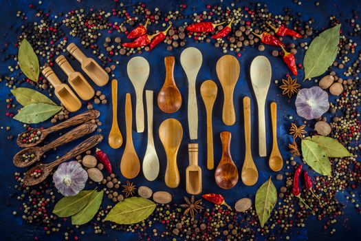 Various spices and wooden spoons on a dark blue background. Spicy background concept with various wooden spoons.  Cooking at home. Top view, close up, flat-lay.