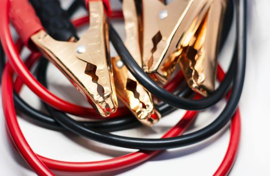 Close up of red and black car battery jumper cable, isolated on white background. Boost cable. Focus on metal