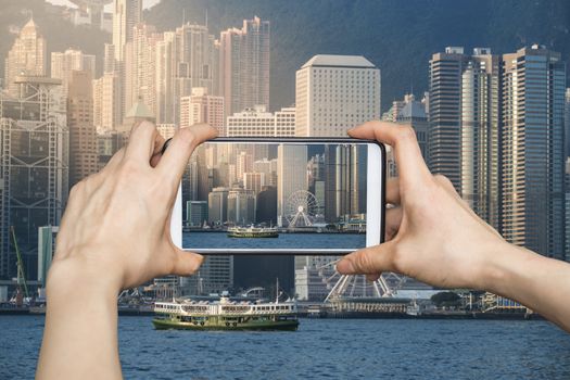 Girl taking pictures on mobile smart phone in Hong Kong's Victoria Harbour in sunrise