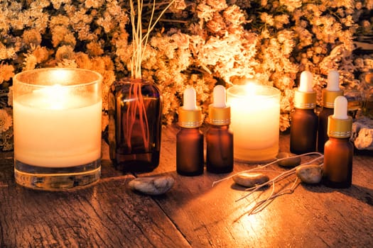 Bottles with organic essential aroma oil with dry flower on old wooden background.