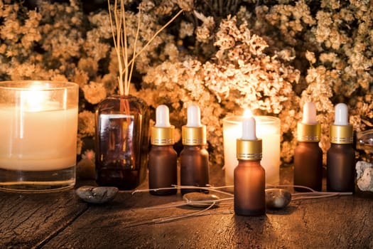 Bottles with organic essential aroma oil with dry flower on old wooden background.