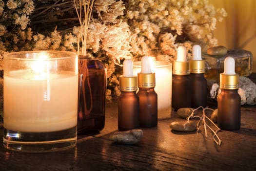 Bottles with organic essential aroma oil with dry flower on old wooden background.