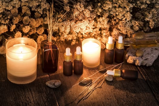 Bottles with organic essential aroma oil with dry flower on old wooden background.