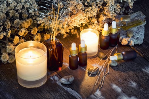 Bottles with organic essential aroma oil with dry flower on old wooden background.