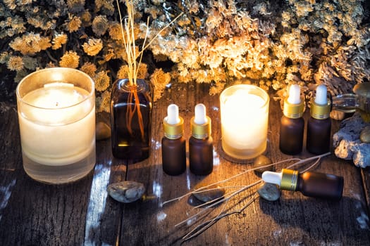 Bottles with organic essential aroma oil with dry flower on old wooden background.