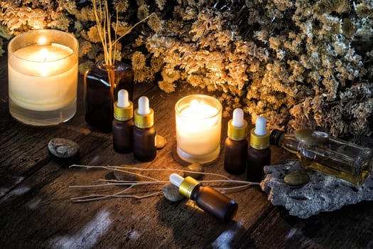 Bottles with organic essential aroma oil with dry flower on old wooden background.