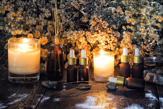 Bottles with organic essential aroma oil with dry flower on old wooden background.