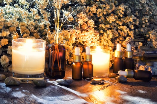 Bottles with organic essential aroma oil with dry flower on old wooden background.