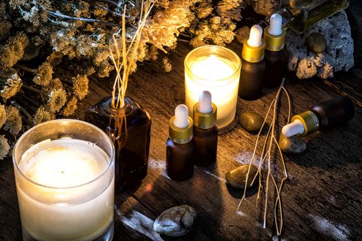 Bottles with organic essential aroma oil with dry flower on old wooden background.