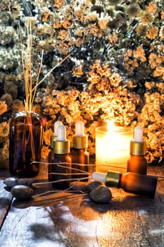 Bottles with organic essential aroma oil with dry flower on old wooden background.