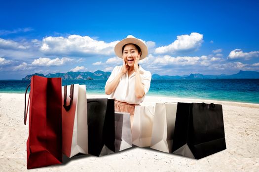 Summer sale a happy shopaholic women opening a shopping bag on the beach