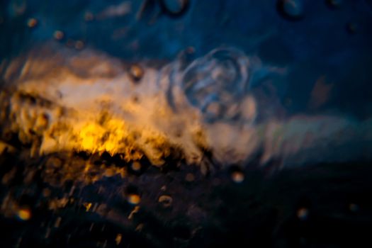 Abstract image of an orange sunset. Shot made through the wave. Sea wave close up, low angle view, sunset shot. Orange sunset on a tropical island in the ocean.