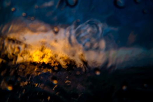 Abstract image of an orange sunset. Shot made through the wave. Sea wave close up, low angle view, sunset shot. Orange sunset on a tropical island in the ocean.