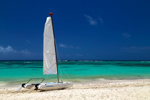 Catamaran on the exotic coast of the Atlantic Ocean with a background from golden sand of emerald water and the blue sky. Beautiful Carribean sea, panoramic view from the beach. Picture with copy space.