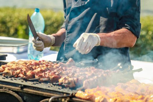 Hand in glove holds a skewer with a kebab made of meat