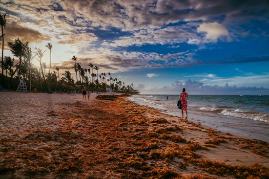 Beautiful cloudscape over the sea, sunset shot. Aerial view over the sea, sunrise shot. Colorful clouds in sunrise over Atlantic Ocean coast. Silhouette of a girl walking along the beach at a beautiful sunset. Bavaro beach. Hispaniola Island. Dominican Republic, coastal landscape.