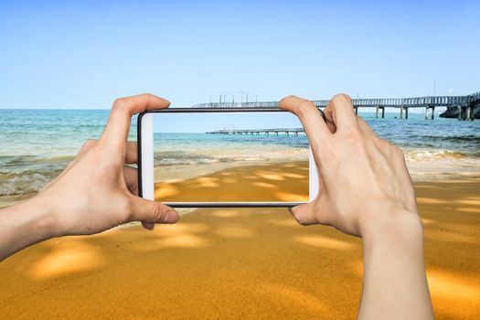 Girl taking pictures on mobile smart phone in Wave on the sand beach