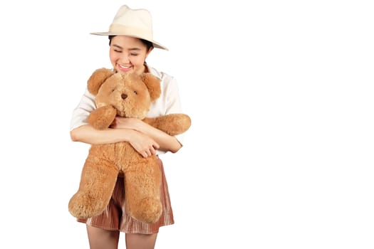 Lovely smiling young woman with hat holding big soft teddy bear on white background 
