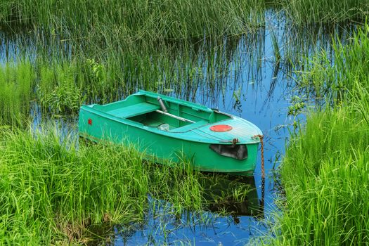 Old metal rowboat moored on the lake 