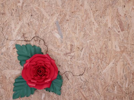 A beautiful hand-crafted paper crimson red rose with thorny veins on vintage wooden board background.