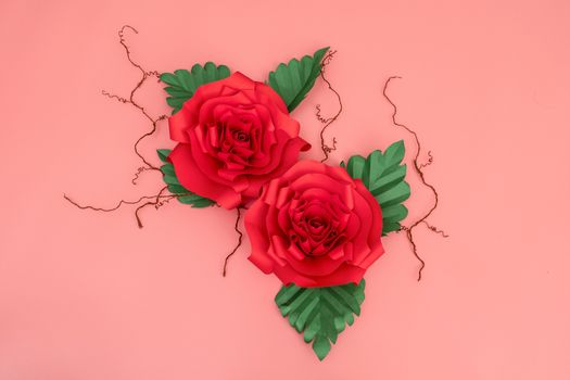 Two paper roses and dried veins on salmon pink background.