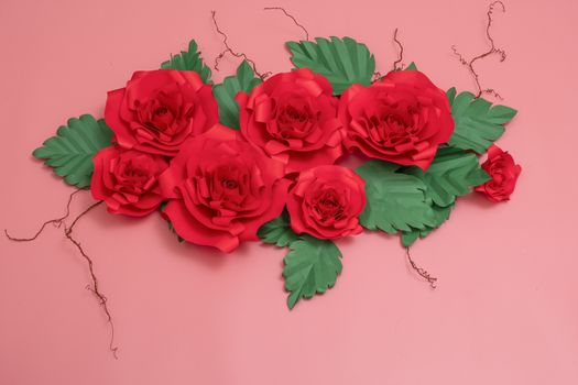 A group of paper roses and dried veins on salmon pink background.
