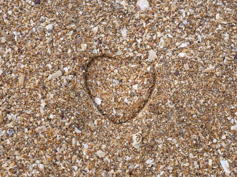 A heart impression on a sand at a sandy beach.