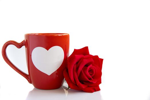 Closeup of an orange coffee mug with a beautiful blooming red rose on white backbround. Valentine's, anniversary, wedding concept.