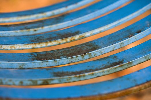 Closeup of a rusty blue metal seat of a swing in a children playground.