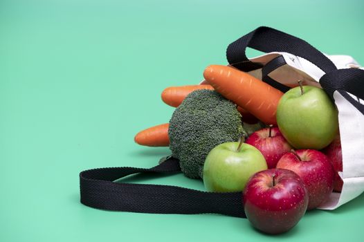 Apples and vegetables in cloth bag . Cloth bag campaign advertising and healthy living concepts. Green background.