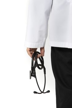 A standing male doctor in long white hospital gown holding a black stethoscope. Isolated on white background.
