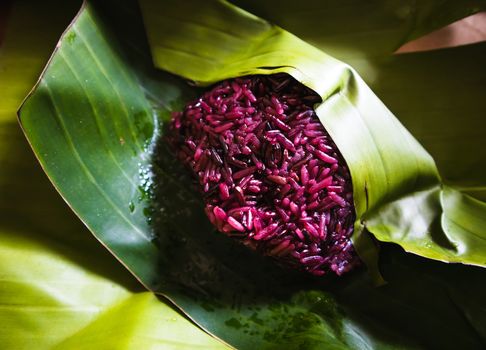 Steamed Purple sticky rice on banana leaf package close up shot. Organic food background concept.
