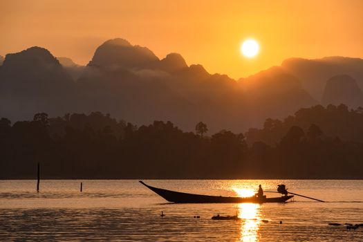 silhouette image of a  boat sailing in a dam in southern of Thailand in the morning.