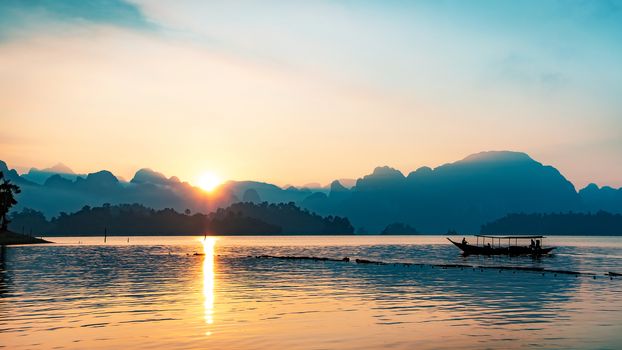 silhouette image of a  boat sailing in a dam in southern of Thailand in the morning.