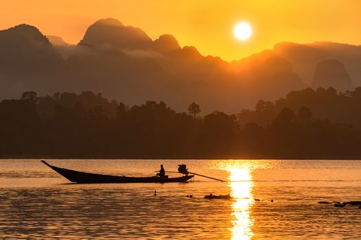 silhouette image of a  boat sailing in a dam in southern of Thailand in the morning.