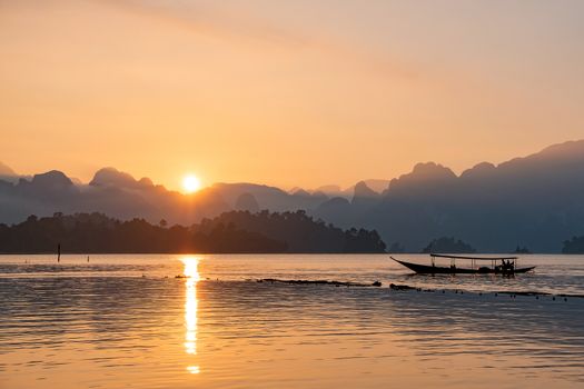 silhouette image of a  boat sailing in a dam in southern of Thailand in the morning.