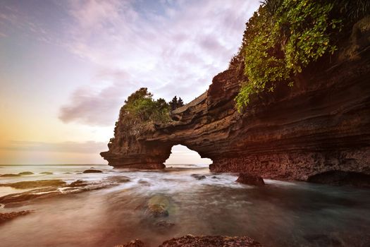 Sunset near famous tourist landmark of Bali island - Tanah Lot & Batu Bolong temple. Long exposure effect, Bali Indonesia. Tropical nature landscape of Indonesia, Bali.