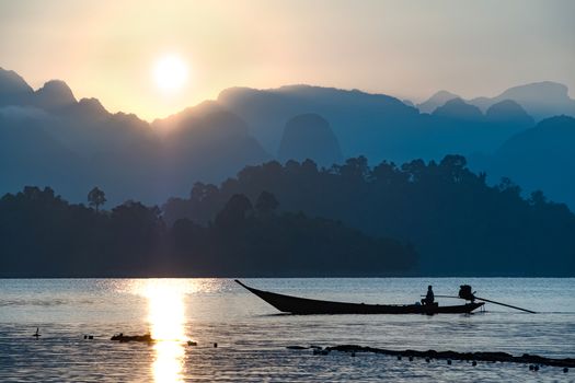 silhouette image of a  boat sailing in a dam in southern of Thailand in the morning.