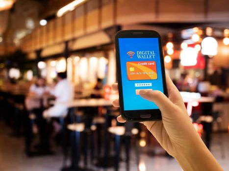 Ecommerce, smart pay, business and technology concept.A digital wallet to pay for goods and services to convenient and fast with blur restaurant background.