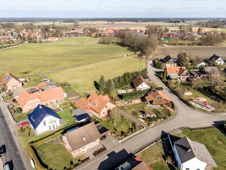 Obliquely photographed aerial view of the edge of a village with houses and a grassy area in the background, which forms a gap in the current location., made with drone