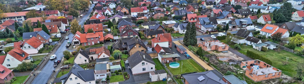 Aerial view of a suburb in Germany with detached houses, streets and gardens. New houses under construction, drone landscape